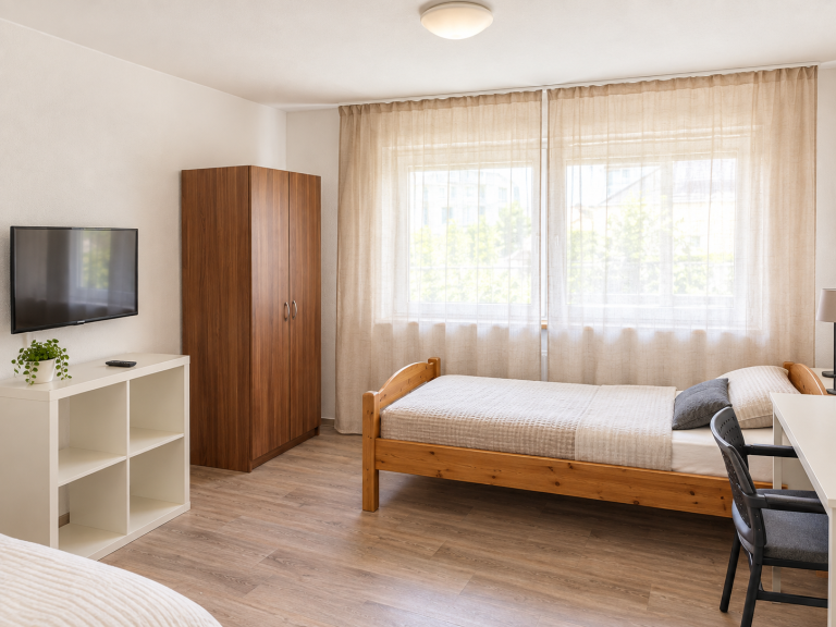 Doppelzimmer Helles Zimmer mit zwei Einzelbetten, Tisch, Stühlen und Fenster mit Vorhängen. Monteurzimmer Mannheim